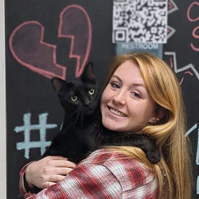 Photo of a woman holding a black cat she just adopted.