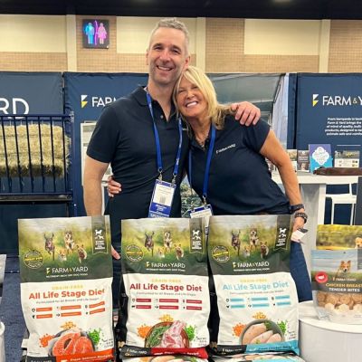 a man and a woman pose surrounded by pet food and brochures