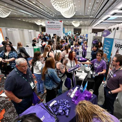 a large group of people speaking with vendors at an exhibit hall