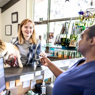 a woman hands her credit card to a vet tech