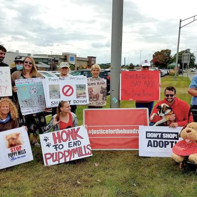 a group of people gathered with signs to end puppy mills