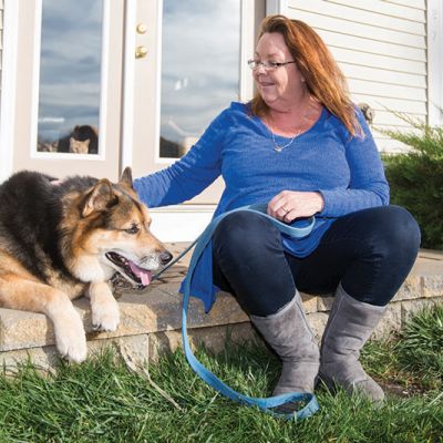 a woman pets her dog while they both sit on a porch
