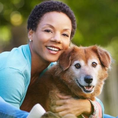 a woman leaning forward to hug her senior dog