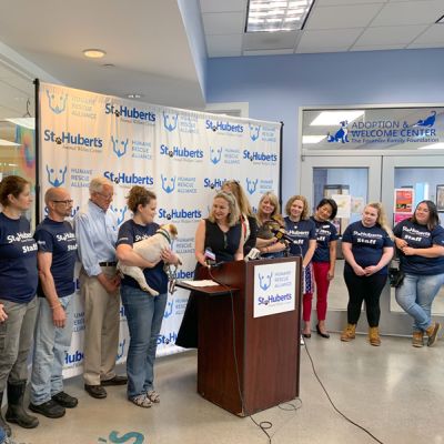 staff from st huberts and humane rescue alliance stand around a podium