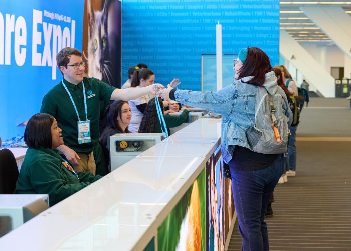Staff handing badge to an attendee at registration desk