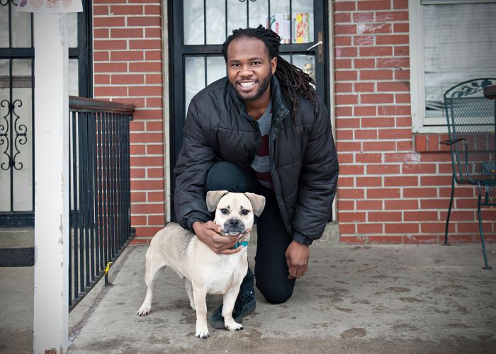 a man poses with his dog on a porch stoop