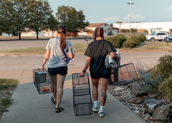 two women walking away carrying humane traps