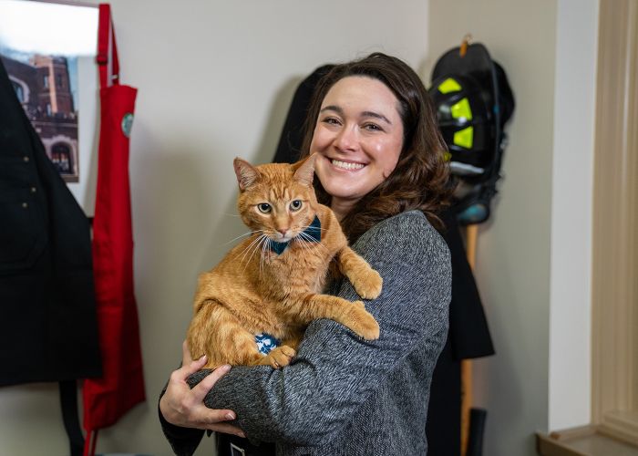 a woman holding an orange cat