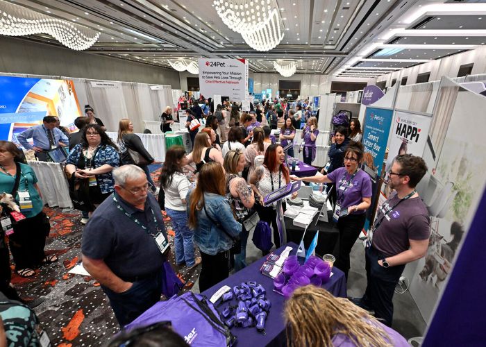 a large group of people speaking with vendors at an exhibit hall