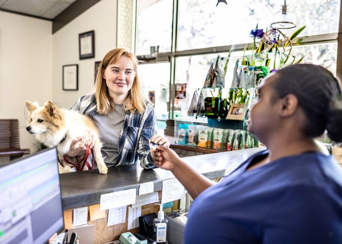 a woman hands her credit card to a vet tech