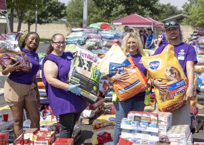 Volunteers holding up bags of pet food