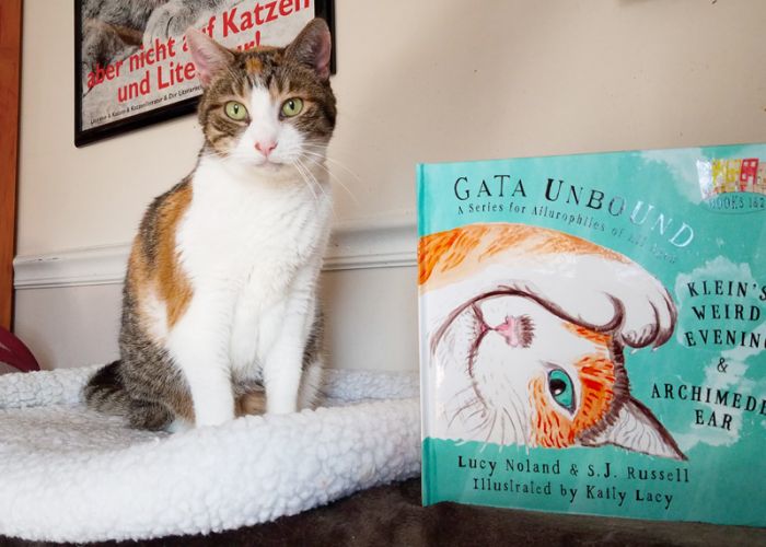 a cat posing alongside the book Gata Unbound
