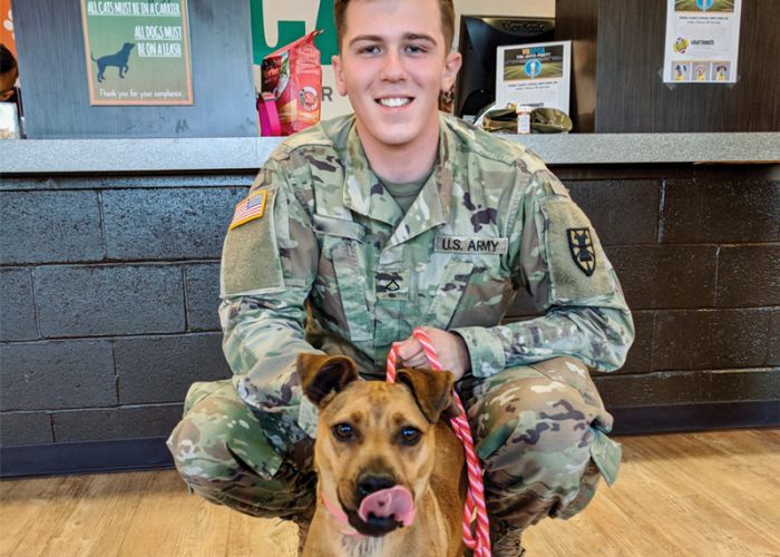 a man in military uniform poses with his shelter dog