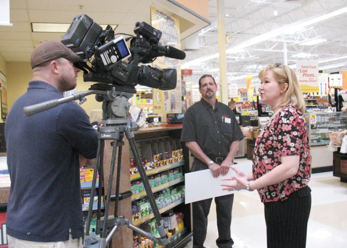 a woman being interviewed in front of a camera in the grocery store