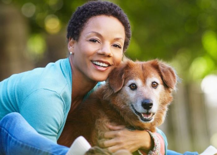 a woman leaning forward to hug her senior dog