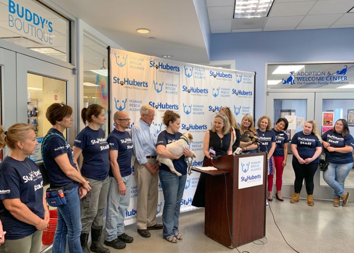 staff from st huberts and humane rescue alliance stand around a podium