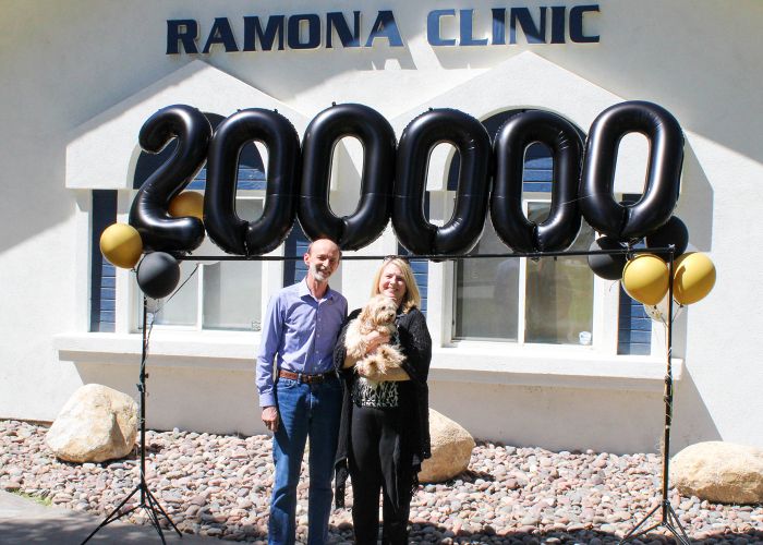 Photo of Dr. Popa with a client and their dog in front of the Romana Clinic.