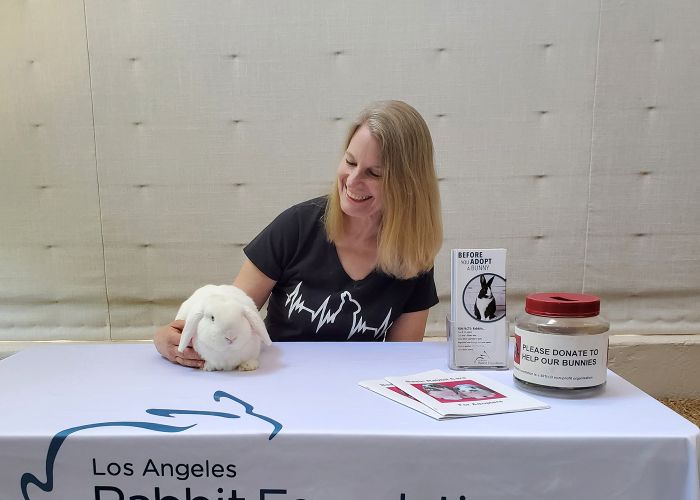 Michelle Kelly sits at a booth for the Los Angeles Rabbit Foundation with a cute white bunny.